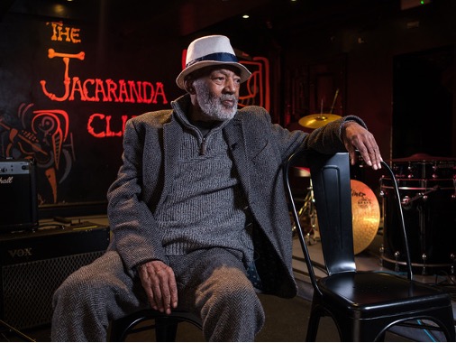 Joe Ankrah sitting on a chair in the Jacaranda
